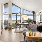 Living and dining area with wooden floor, large windows, and fireplace.