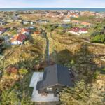 House with terrace in dunes, view of coastal village and sea.