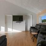 Living room with sofa, TV, and pool table. Wood wall and window with view.