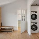 Room with wooden wall, bench, and view into kitchen and laundry