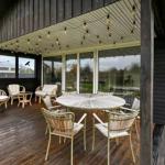 Deck with round table and chairs under string lights.
