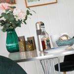 Dining table with green vase, flowers, and drinks