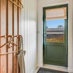 Entrance with green door and wooden coat rack.