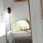 Bedroom with bed, pillows, and standing lamp against the wall.