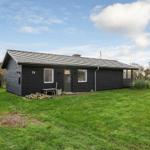 A dark wooden house with a green lawn and clear sky.