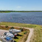 Watersports on the lake, boats by the shore, wind turbines in the distance.