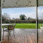 Deck with wooden planks, garden furniture, and string lights under roof