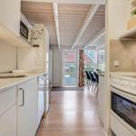 Kitchen with countertop, sink, and stove. Corridor to dining area with table and chairs.