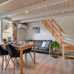 Dining area with table, chairs, and sofa. Wooden stairs lead upstairs.