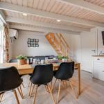 Dining area with table, chairs, and TV. Wooden ceiling and staircase visible.
