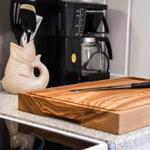 Kitchen counter with cutting board, knife, and coffee maker.