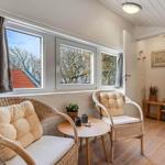 Two chairs and a table are placed in front of a window with a view of trees.