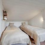 Two beds with patterned bedding in a room with white walls and wooden floor.