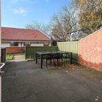 Terrace with table and chairs, surrounded by wall and fence.