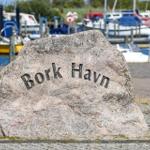 Stone with inscription Bork Havn in front of a harbor with boats.