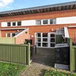 Red brick house with terrace and green fence.