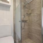 Bathroom with shower and toilet. Shower area with glass door and tiles.