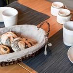 Breakfast table with bread basket, mugs, and candles.