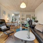Living and dining area with leather sofa, chair, and wooden table.