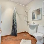 Bathroom with shower, sink and toilet. Terracotta floor and window.