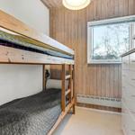 Room with bunk bed, wood wall, and window.