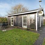 A small house with garden, table and chairs, and satellite dish.