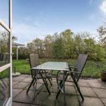 Terrace with table and two chairs, view of a green garden with trees.