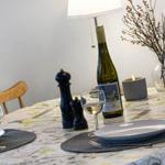 Dining table set for two, wine bottle, glasses, and decor.