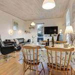 Dining area with wooden table and chairs, living area with sofa and TV.