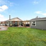 House with garden, terrace, and hot tub. Left utility building. Background with trees.