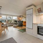 Kitchen with fridge and stove. Dining area with table and chairs. Living area with seating.