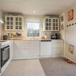 Kitchen with white cabinets, window, and door to outdoor area.
