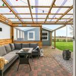 Terrace with seating, string lights, and view of garden and house.