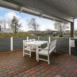Terrace with white table and benches, bordered by gray fence and red bricks.