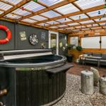 House with hot tub, seating area, and string lights under roof
