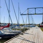 Wooden pier with sailboats and cranes at the harbor