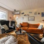 Living room with orange sofa, black chairs, and wood-paneled walls.