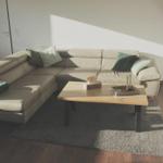 Ein Wohnzimmer mit Ecksofa, Holztisch und Stehlampe.