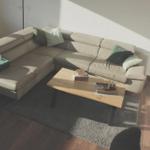 Ein Wohnzimmer mit L-förmigem Sofa, Holztisch und Stehlampe.