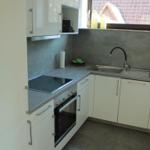 Küche mit weißen Schränken, Edelstahlspüle und Fenster mit Blick auf Dach