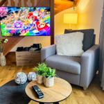 Wohnzimmer mit Sessel, Fernseher und Holzboden.