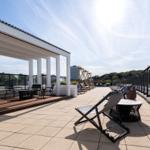 Terrasse mit Sonnenliegen, Tischen und Sitzgelegenheiten unter freiem Himmel.