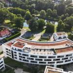 Moderne Wohnanlage mit begrüntem Dach und Blick auf einen ruhigen See.