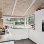 Kitchen with white cabinets, wooden ceiling, and large windows to the forest.