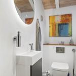 Bathroom with sink, toilet, and shower. Wall art and wooden ceiling.