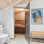 Bathroom with sauna, shower, and wooden floor. A painting hangs on the wall.