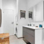 Bathroom with washing machine, mirror cabinet, and towel racks.