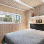 Bedroom with wooden walls, bed, and window.