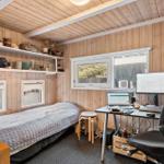 A bedroom with desk, bed, and windows on the walls.