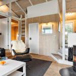 Living room with fireplace, sofa, and chair. Wooden walls and floor. Door to bedroom.